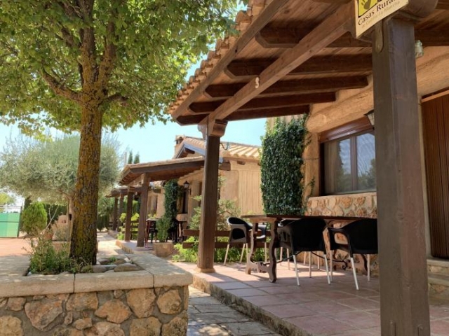 Porche de madera y piedra de una cabaña con mesa exterior