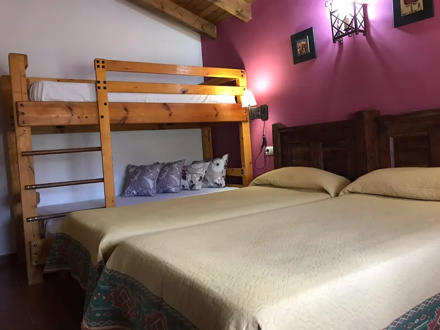 Dormitorio con litera de madera y dos camas individuales juntas en una cabaña de El Acuífero