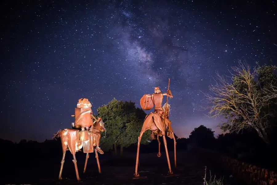 Esculturas de hierro de Don Quijote y Sancho Panza en la entrada de la Cueva de Montesinos, recortadas bajo la Vía Láctea